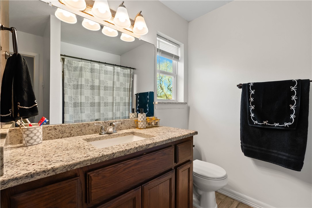 985 Ribbontail Street Corpus Christi, TX 78418 - Photo 13 of 15 a bathroom with a granite countertop sink a toilet and a mirror