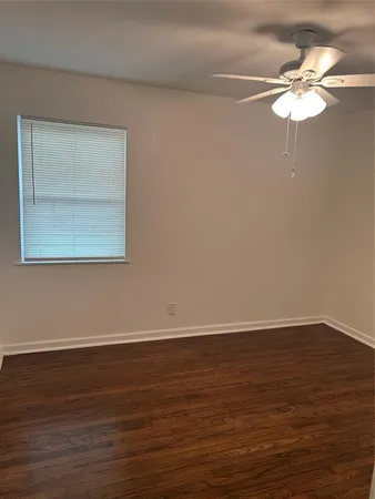 a view of an empty room with wooden floor and a chandelier