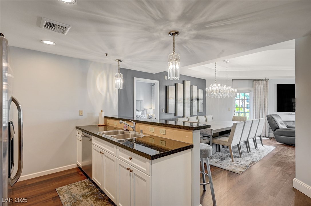 30 Strada Di Villaggio, Unit 250 Henderson, NV 89011 - Photo 12 of 52 Kitchen with a peninsula, a kitchen bar, dark wood-style floors, stainless steel appliances, and white cabinetry