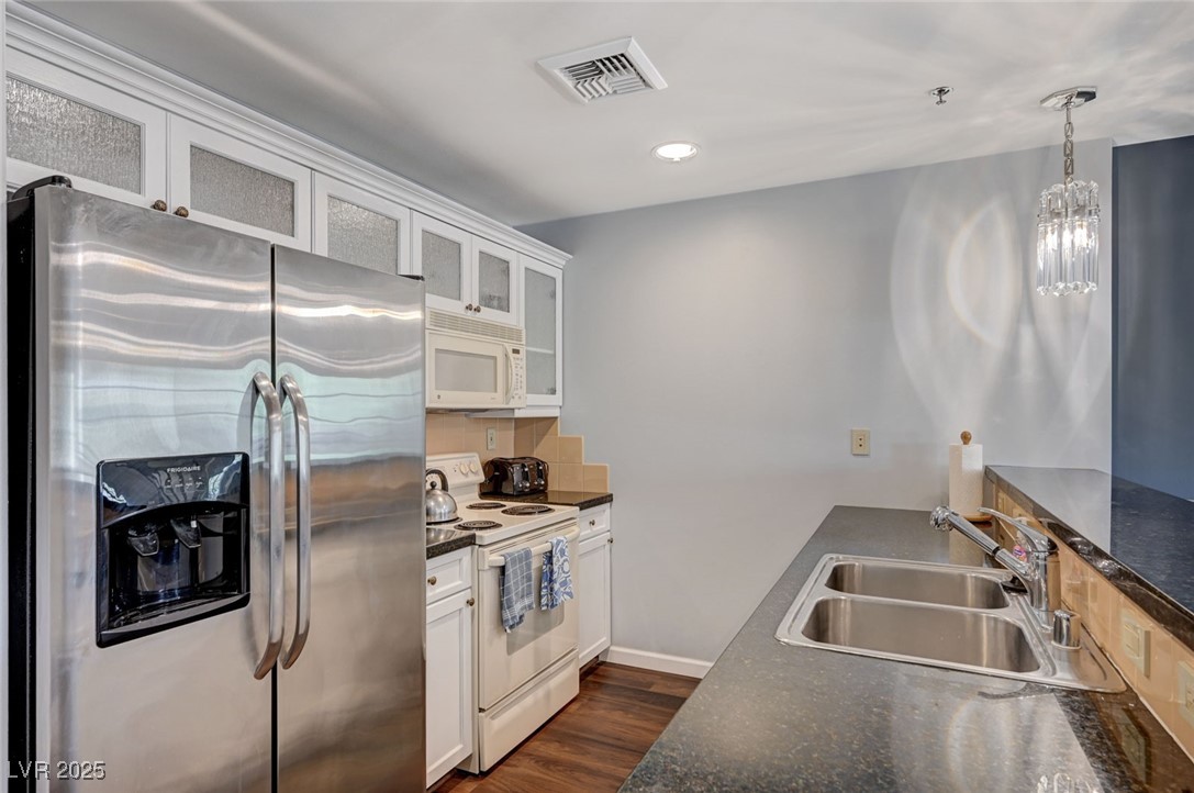 30 Strada Di Villaggio, Unit 250 Henderson, NV 89011 - Photo 13 of 52 Kitchen featuring white appliances, pendant lighting, glass insert cabinets, white cabinetry, and dark wood-style floors