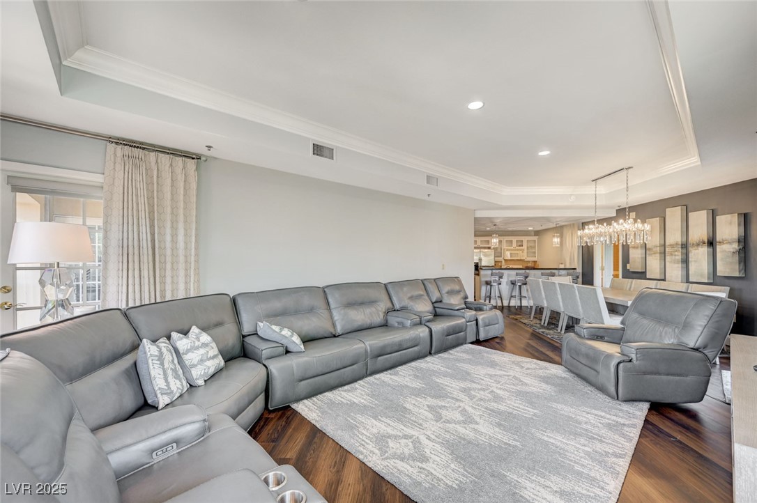 30 Strada Di Villaggio, Unit 250 Henderson, NV 89011 - Photo 8 of 52 Living area featuring a raised ceiling, dark wood-style flooring, ornamental molding, recessed lighting, and a chandelier