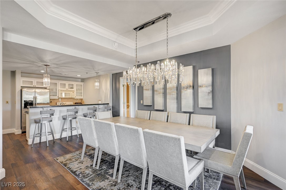 30 Strada Di Villaggio, Unit 250 Henderson, NV 89011 - Photo 9 of 52 Dining area featuring a tray ceiling, ornamental molding, dark wood-type flooring, and a chandelier