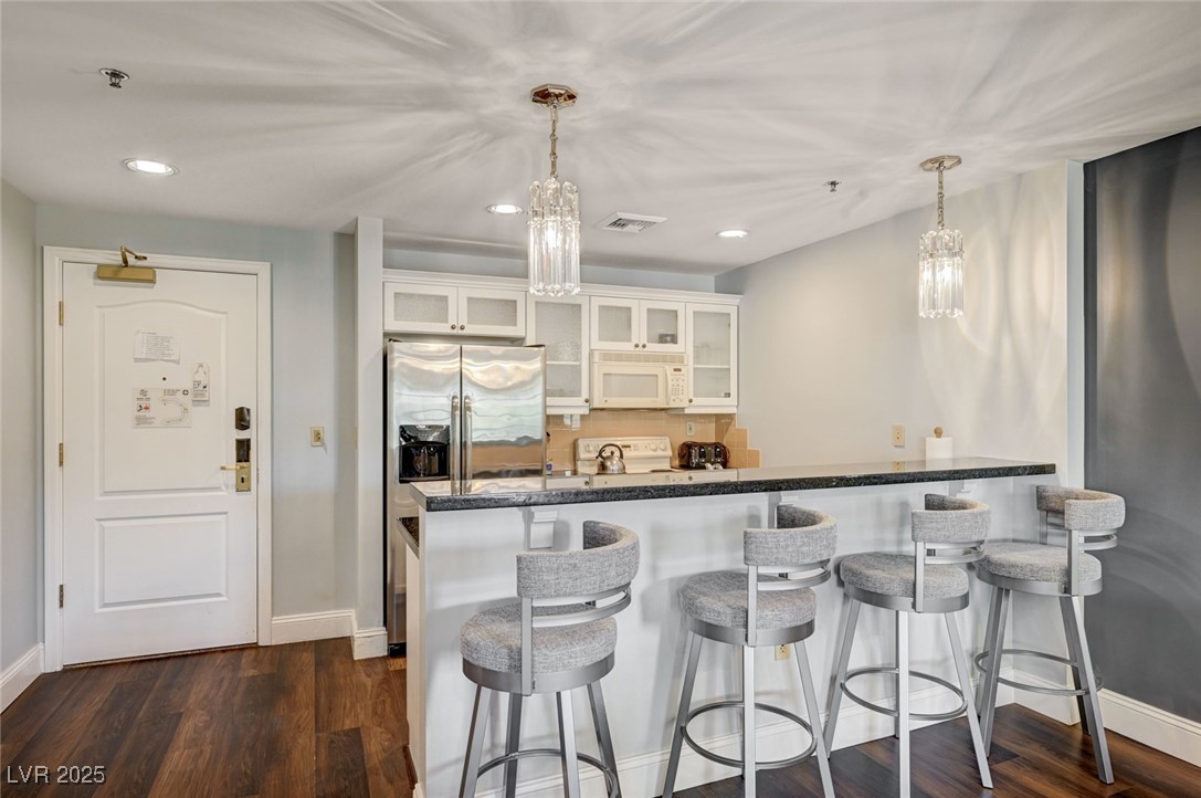 30 Strada Di Villaggio, Unit 250 Henderson, NV 89011 - Photo 10 of 52 Kitchen featuring a chandelier, glass insert cabinets, recessed lighting, white appliances, and a kitchen breakfast bar