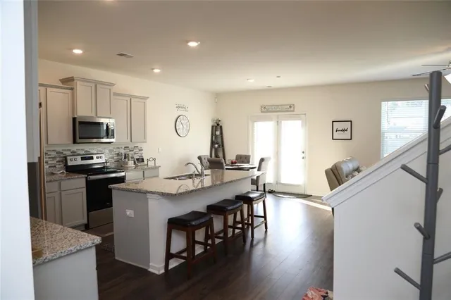 a kitchen with stainless steel appliances granite countertop a kitchen island hardwood floor sink stove dining table and chairs