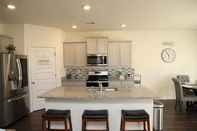 a kitchen with stainless steel appliances granite countertop a table chairs microwave and refrigerator