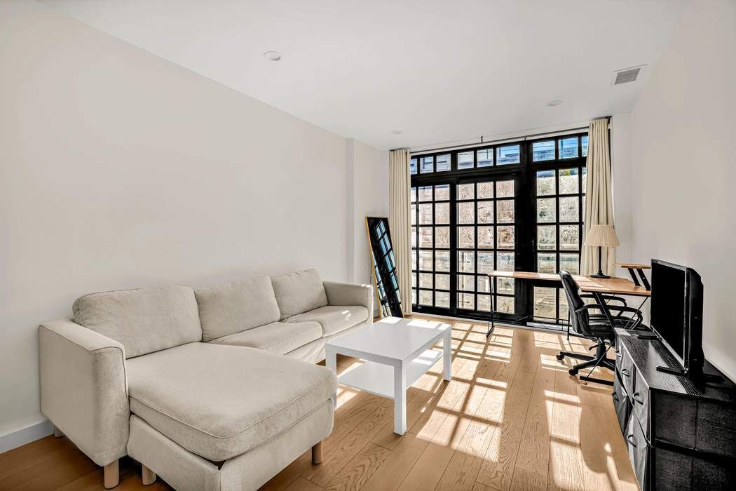 37-24 30th Street, Unit 2F Queens, NY 11101 - Photo 3 of 12 a living room with furniture and a floor to ceiling window