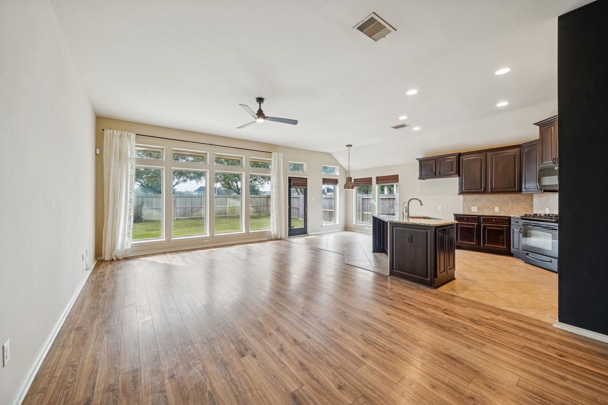 13014 Barkley Bend Lane Houston, TX 77044 - Photo 2 of 42 Expansive first-floor living areas boast an open layout that seamlessly connects the kitchen and breakfast nook. Large windows overlook the backyard, flooding the space with natural light and providing direct access to the outdoor patio. The kitchen features granite countertops, a gas range, and a functional island with a breakfast bar, ideal for casual dining or entertaining.