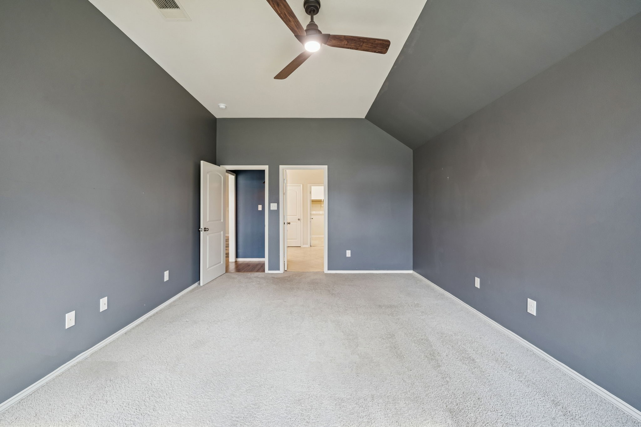 13014 Barkley Bend Lane Houston, TX 77044 - Photo 24 of 42 Bold gray walls and a vaulted ceiling elevate this secondary bedroom, which easily serves as a versatile flex space. Plush neutral carpeting and a modern wood-blade ceiling fan ensure comfort, while the open layout provides easy access to the hallway and nearby utility room. This private retreat offers a clean, contemporary aesthetic for various furniture arrangements.