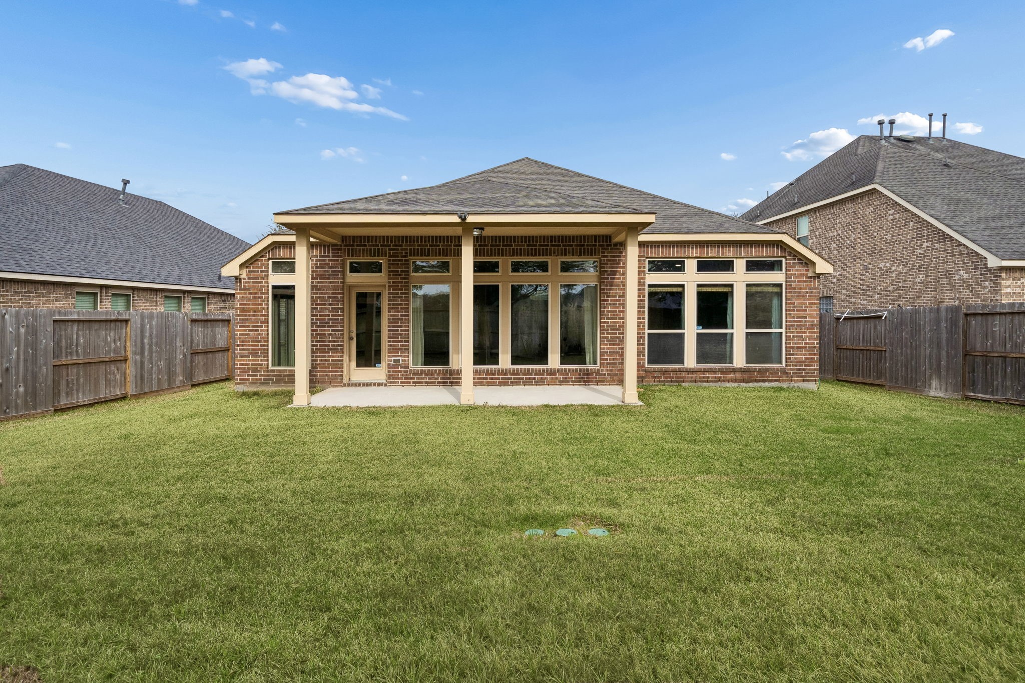 13014 Barkley Bend Lane Houston, TX 77044 - Photo 34 of 42 Lush green lawn and a sturdy wood fence define this expansive backyard, offering plenty of room for outdoor activities. The rear elevation of this one-story brick home features a covered patio and a wide array of oversized windows that bridge the gap between the interior living spaces and the serene outdoor retreat. Centrally located in Lakeshore, this lot provides long-term value and privacy.