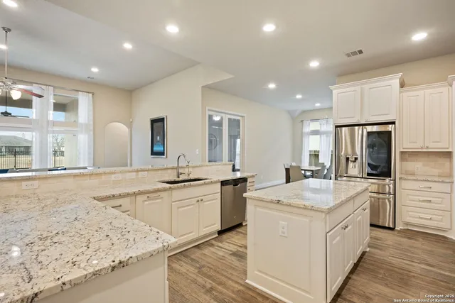 a large white kitchen with kitchen island white cabinets and stainless steel appliances