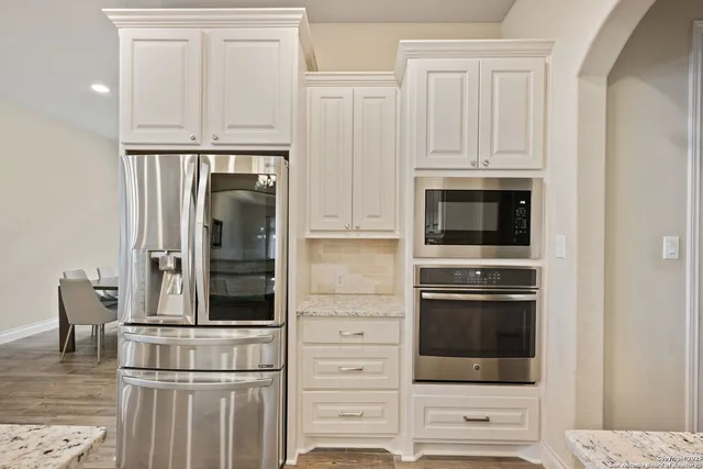 a kitchen with white cabinets and stainless steel appliances