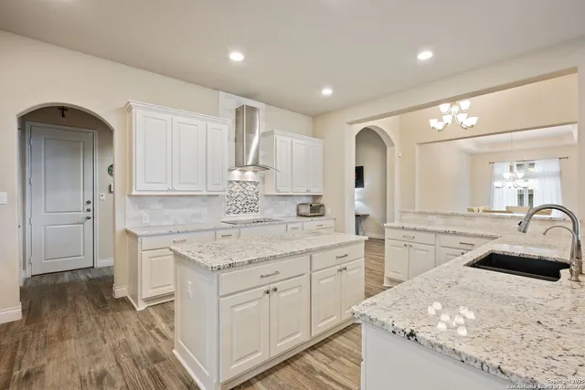a kitchen with a sink dishwasher a stove and white cabinets with wooden floor