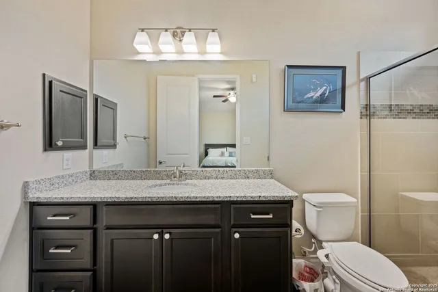 a bathroom with a granite countertop toilet sink and mirror