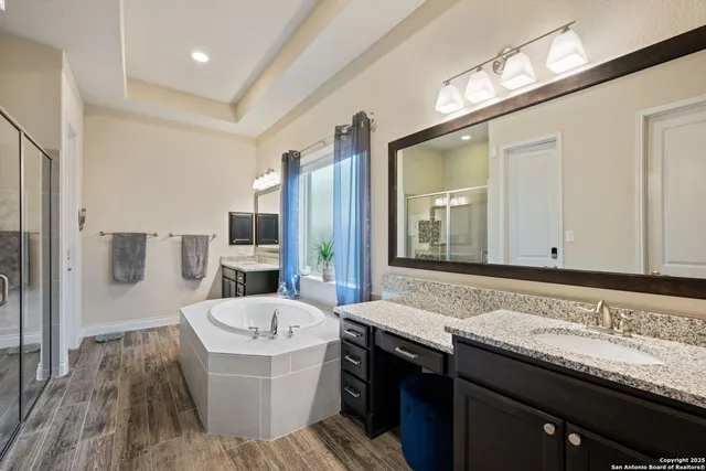 a bathroom with a granite countertop bathtub a sink and a large mirror