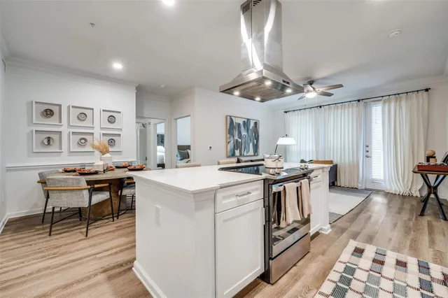 a open kitchen with stainless steel appliances granite countertop a stove top oven a dining table and chairs with wooden floor