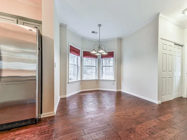 a view of an empty room with window and wooden floor