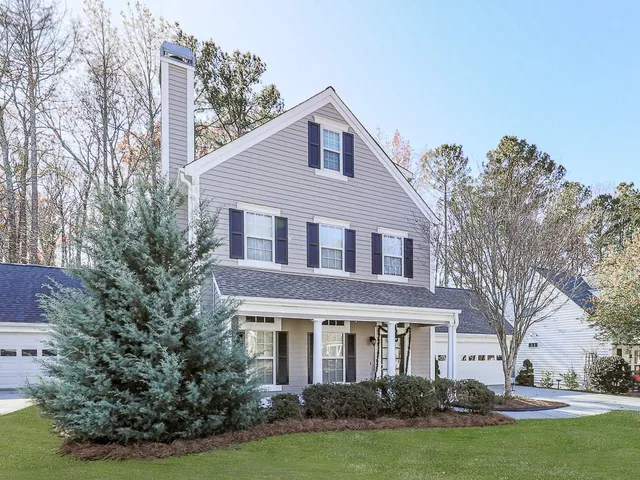 a front view of a house with a garden and trees