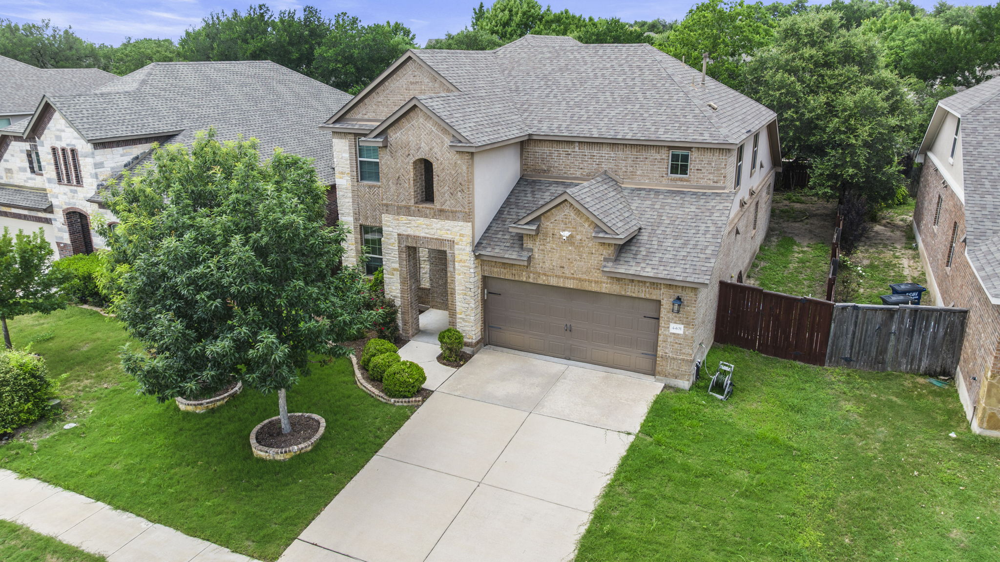 4401 Trinity Woods Street Leander, TX 78641 - Photo 34 of 37 A classic brick and stone facade welcomes with mature landscaping and a well-maintained driveway.