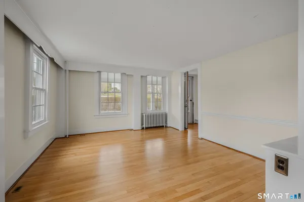 a view of an empty room with window and wooden floor