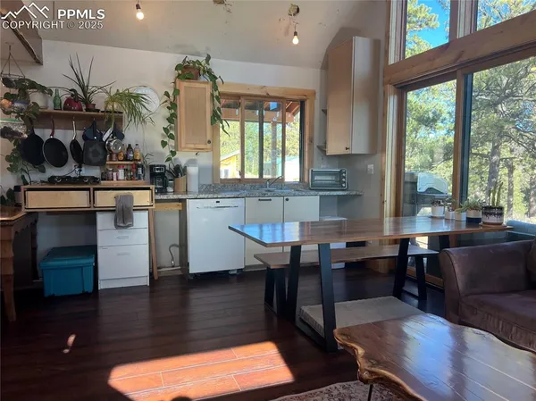 a kitchen with stainless steel appliances granite countertop a sink dishwasher a stove a dining table and chairs with wooden floor