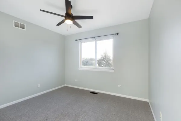 an empty room with a window and a fan