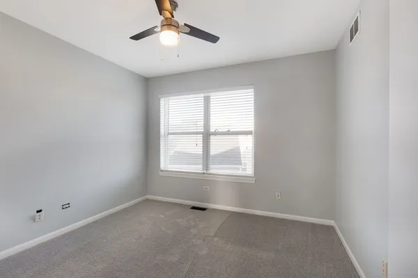 an empty room with a window and a fan