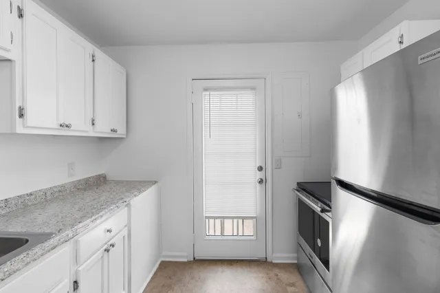 a kitchen with granite countertop white cabinets and refrigerator