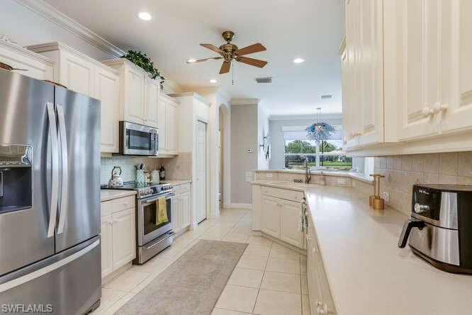 9871 Rookery Circle Estero, FL 33928 - Photo 13 of 38 a kitchen with stainless steel appliances a stove a refrigerator a sink a oven with white cabinets and wooden floor