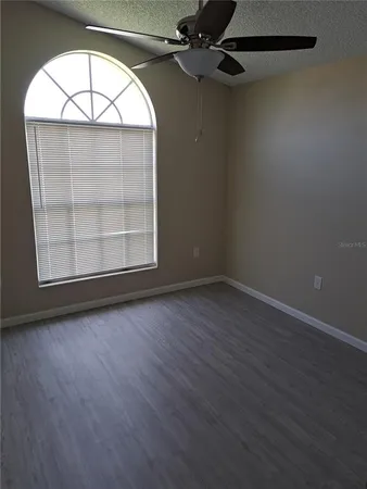 an empty room with wooden floor cabinet and windows