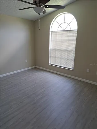an empty room with wooden floor exposed radiator and windows