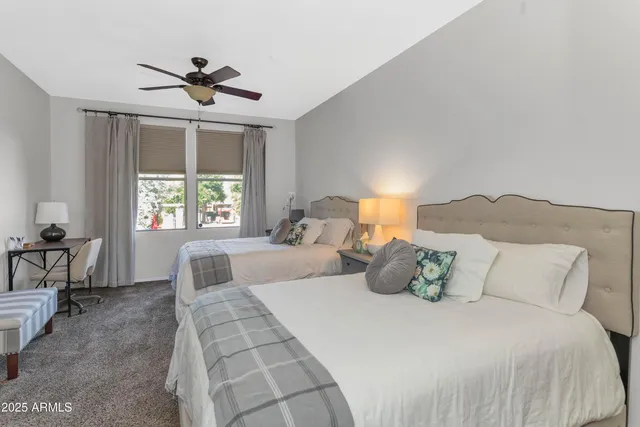 a bedroom with a large bed and two windows