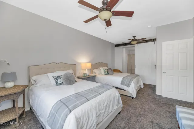 a bedroom with two beds and ceiling fan