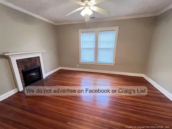 a view of an empty room with wooden floor and a fireplace