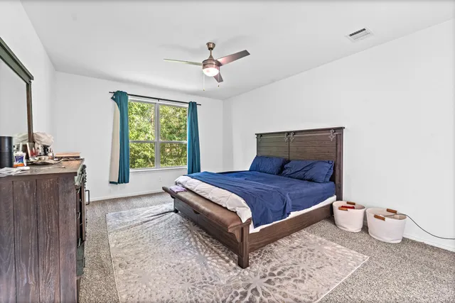 a bed sitting in a spacious bedroom next to a window