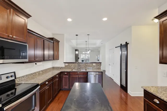 a large kitchen with stainless steel appliances granite countertop a stove refrigerator and cabinets