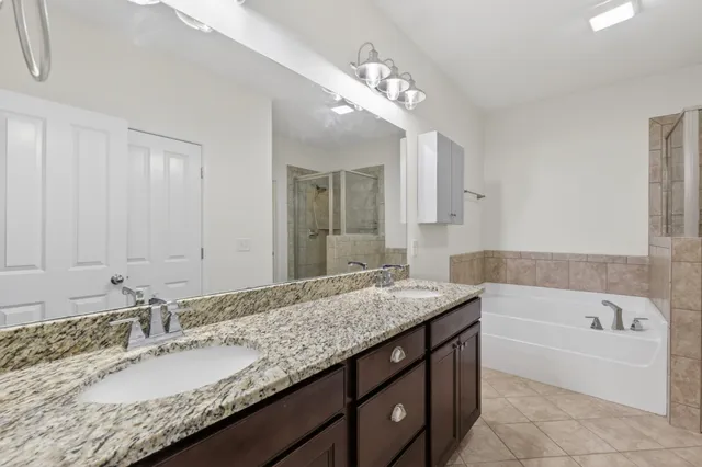 a bathroom with a granite countertop bathtub a double vanity sink and a mirror