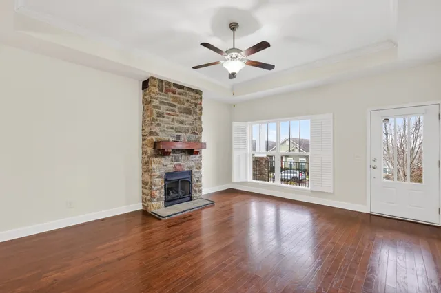 an empty room with wooden floor chandelier fan and windows