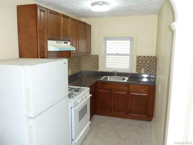 a kitchen with granite countertop a stove a sink and a microwave