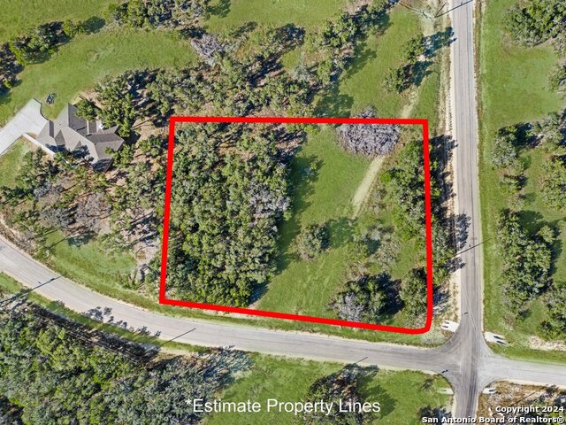 The property features a combination of wooded and grassy areas, with visible road access