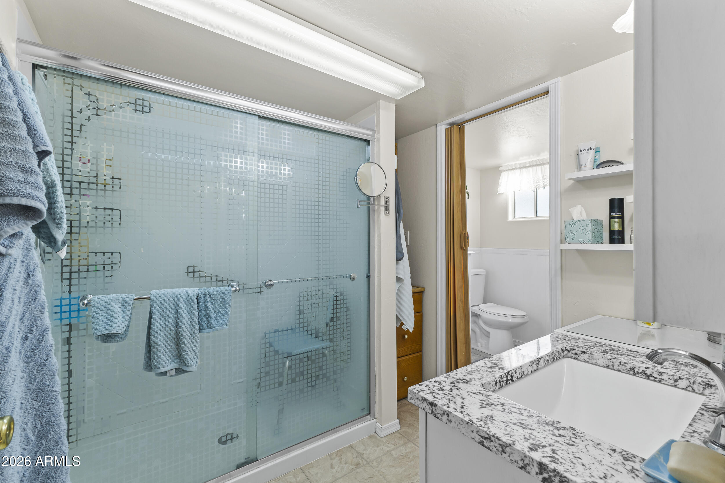 17200 West Bell Road, Unit 548 Surprise, AZ 85374 - Photo 16 of 19 a bathroom with a granite countertop sink a mirror and shower