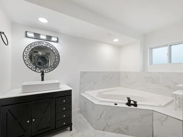 a bathroom with a bathtub a sink and a mirror