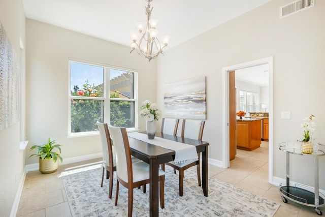 a dining room with furniture a rug a potted plant and a chandelier