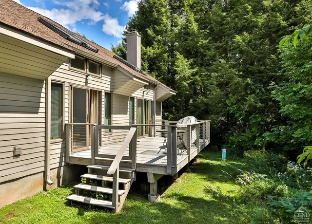a white house that has a small yard and couches chairs with wooden fence