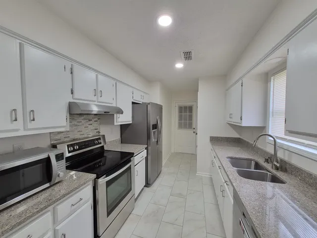 a kitchen with stainless steel appliances granite countertop a sink stove and refrigerator