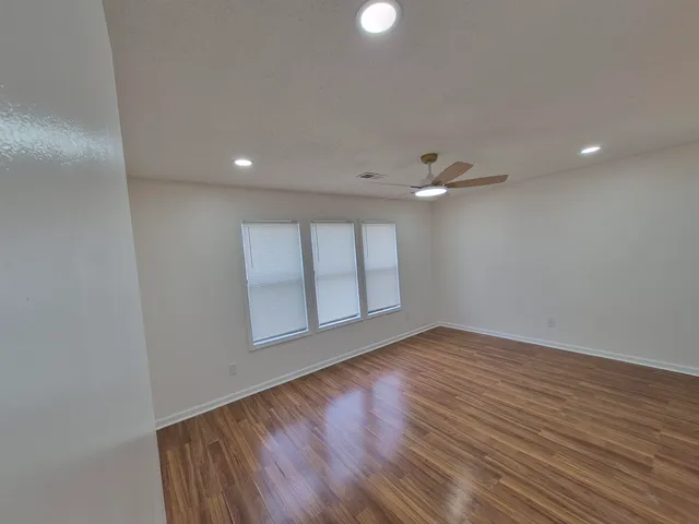 a view of empty room with wooden floor and fan