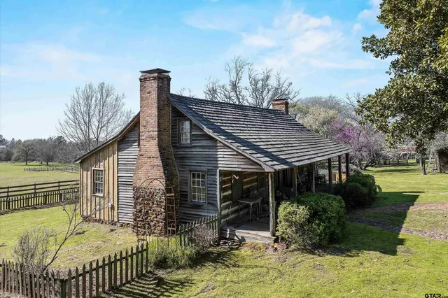 a front view of house with garden and trees in the background