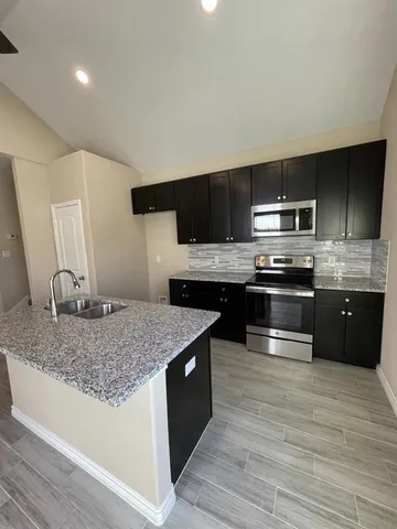a kitchen with stainless steel appliances granite countertop a sink and a stove top oven
