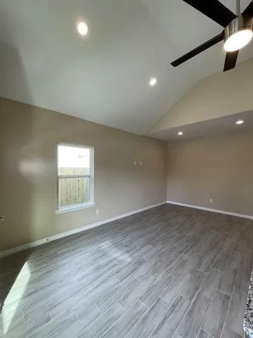 an empty room with a chandelier fan and windows