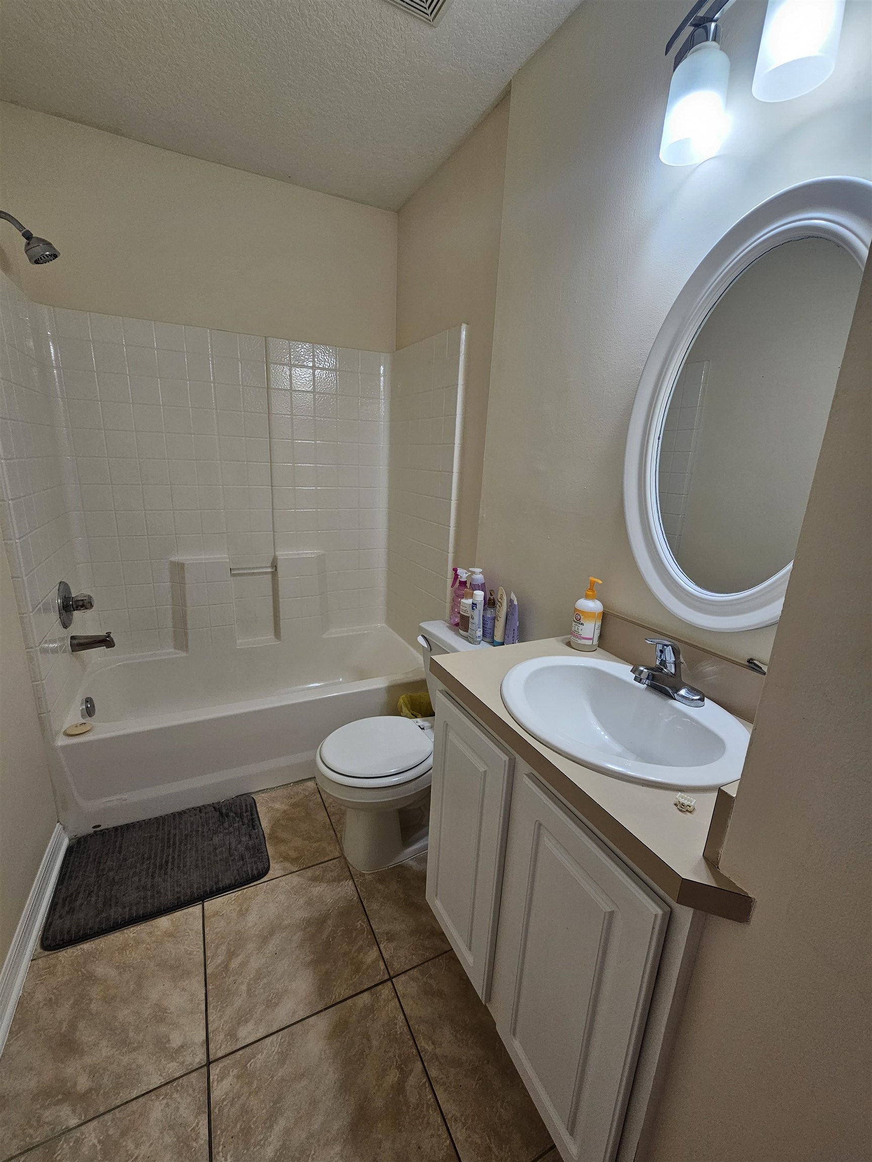 985 Cooper Street St. Augustine, FL 32084 - Photo 12 of 12 Full bathroom with bathtub / shower combination, a textured ceiling, vanity, and light tile patterned flooring