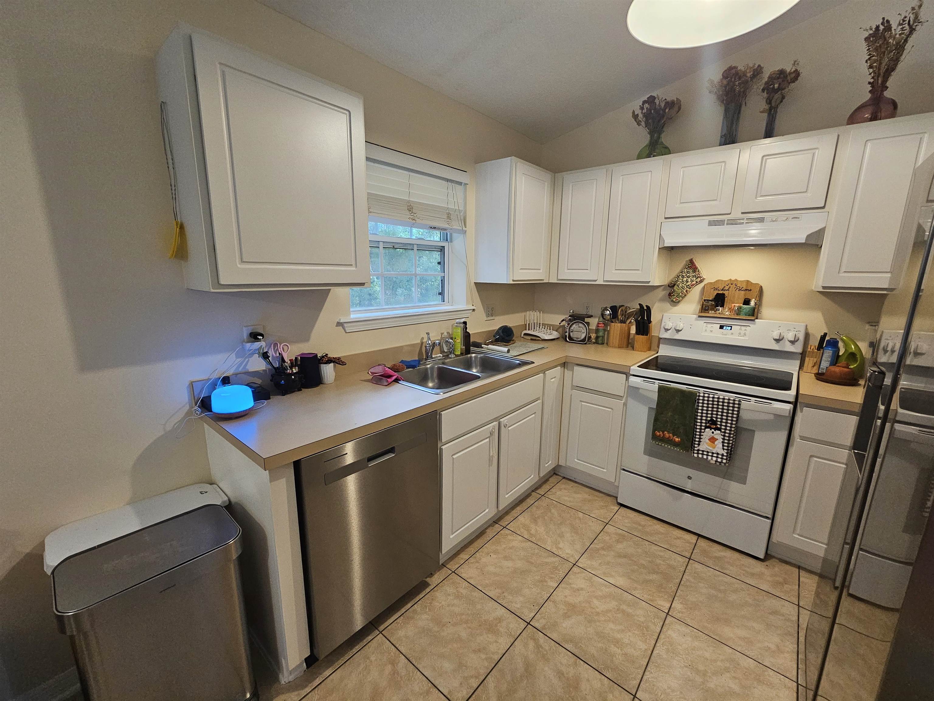 985 Cooper Street St. Augustine, FL 32084 - Photo 6 of 12 Kitchen with stainless steel appliances, light countertops, white cabinetry, light tile patterned floors, and lofted ceiling